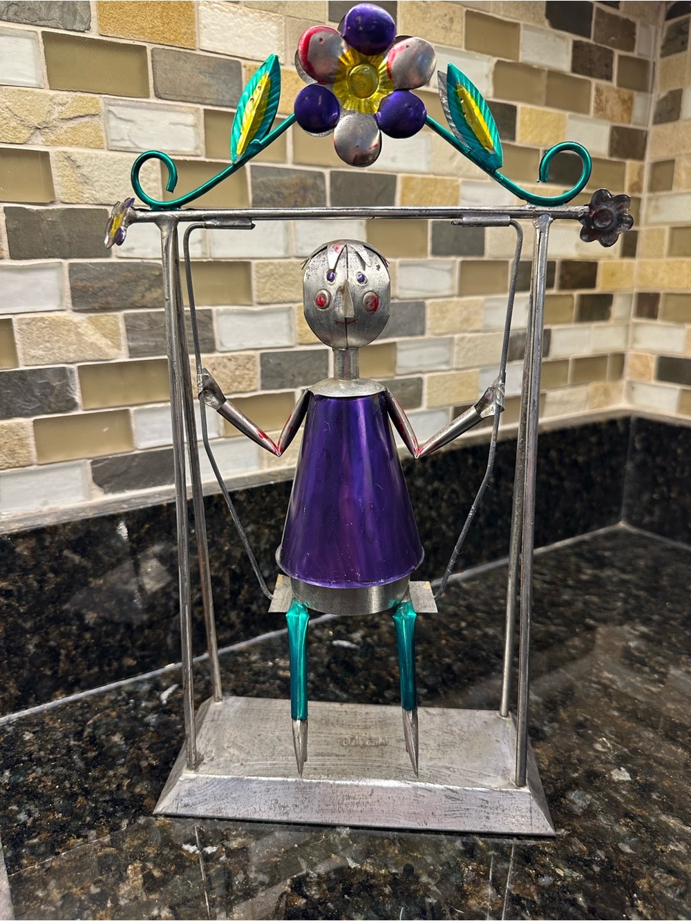 Vintage, colorful Mexico metal figurine on swing